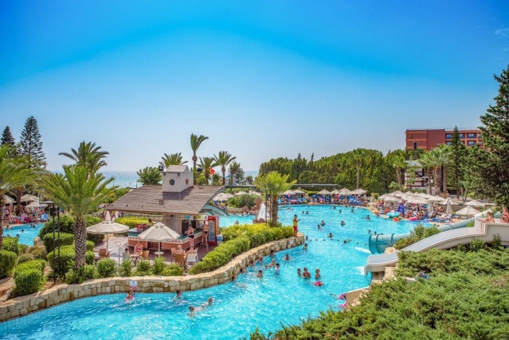 Pool area with palm trees and people.
