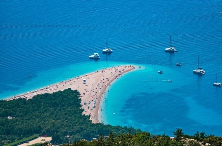 Beach with turquoise water and boats.