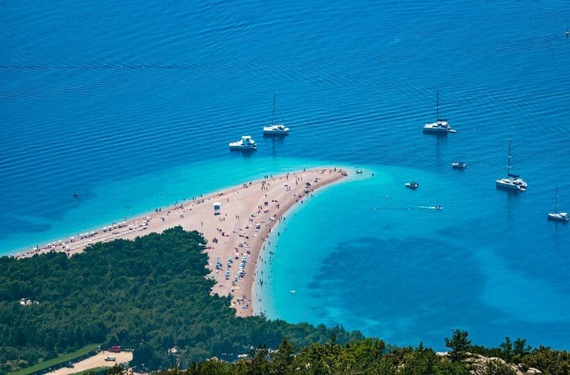 Beach with turquoise water and boats.