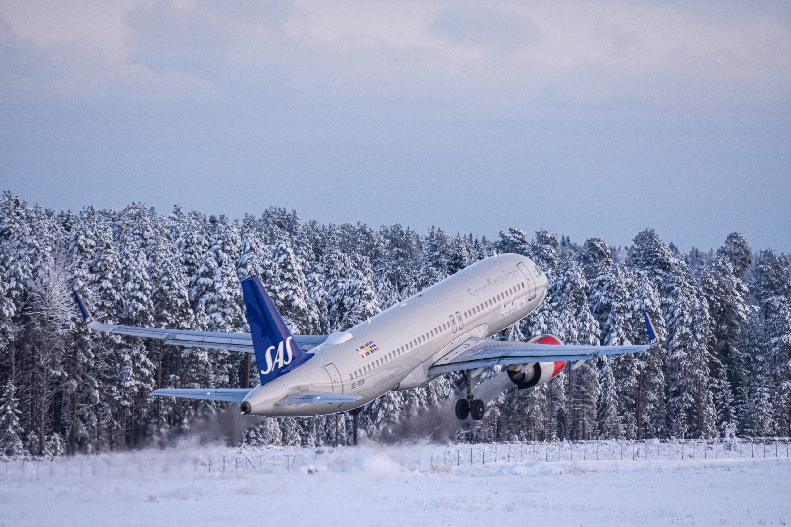 Flygplan lyfter från snötäckt landningsbana